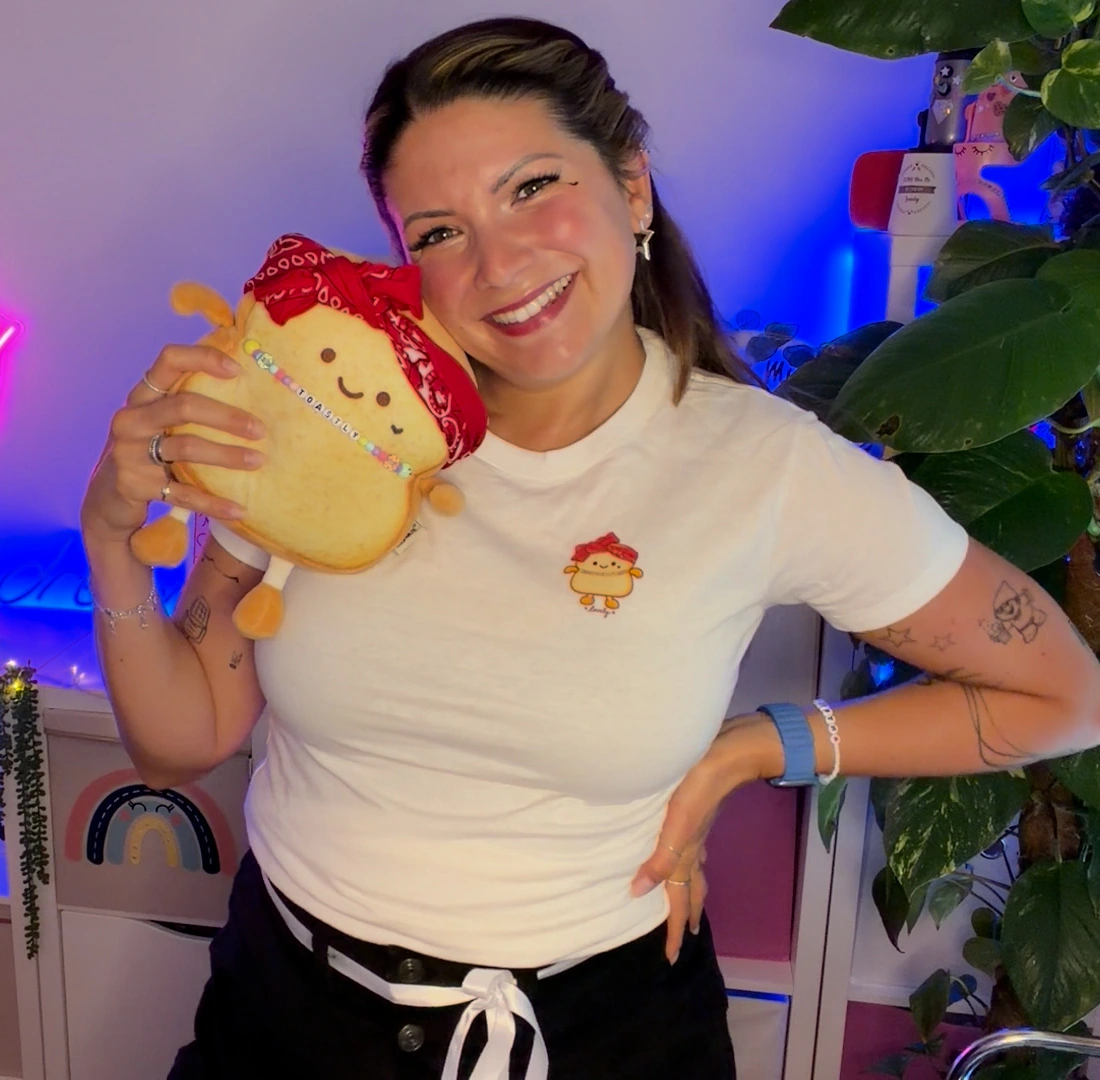 Miss Mi hält Toastly neben ihr Gesicht und trägt das echte Toastly-Shirt bei ihrer Anprobe.